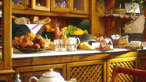 Uma mesa de madeira com pão, pastelaria e bebidas para o pequeno-almoço.