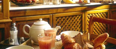 A breakfast setting with bread, pastries, and beverages on a wooden table.
