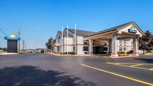 A Days Inn with a gas station sign, a covered parking area, and a clear blue sky.