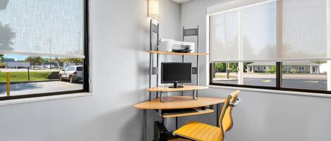 A corner office with a desk, chair, computer, and printer.