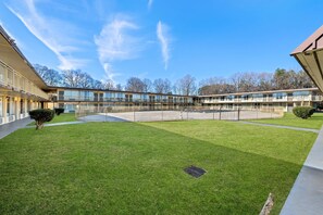 A courtyard with a pool, a building with multiple floors, and a clear sky.