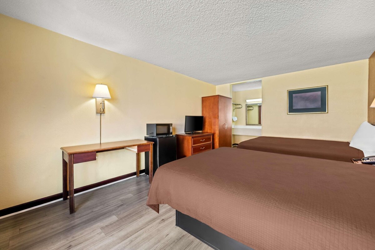 A hotel room with a bed, a desk, a television, and a cabinet.