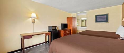A hotel room with a bed, a desk, a TV, a dresser, and a lamp.