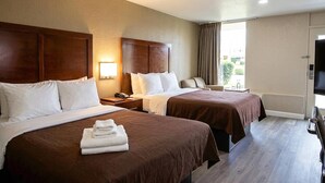 A hotel room with two beds, a desk, a chair, a TV, and a window with curtains. - Rodeway Inn Monroe (Monroe)