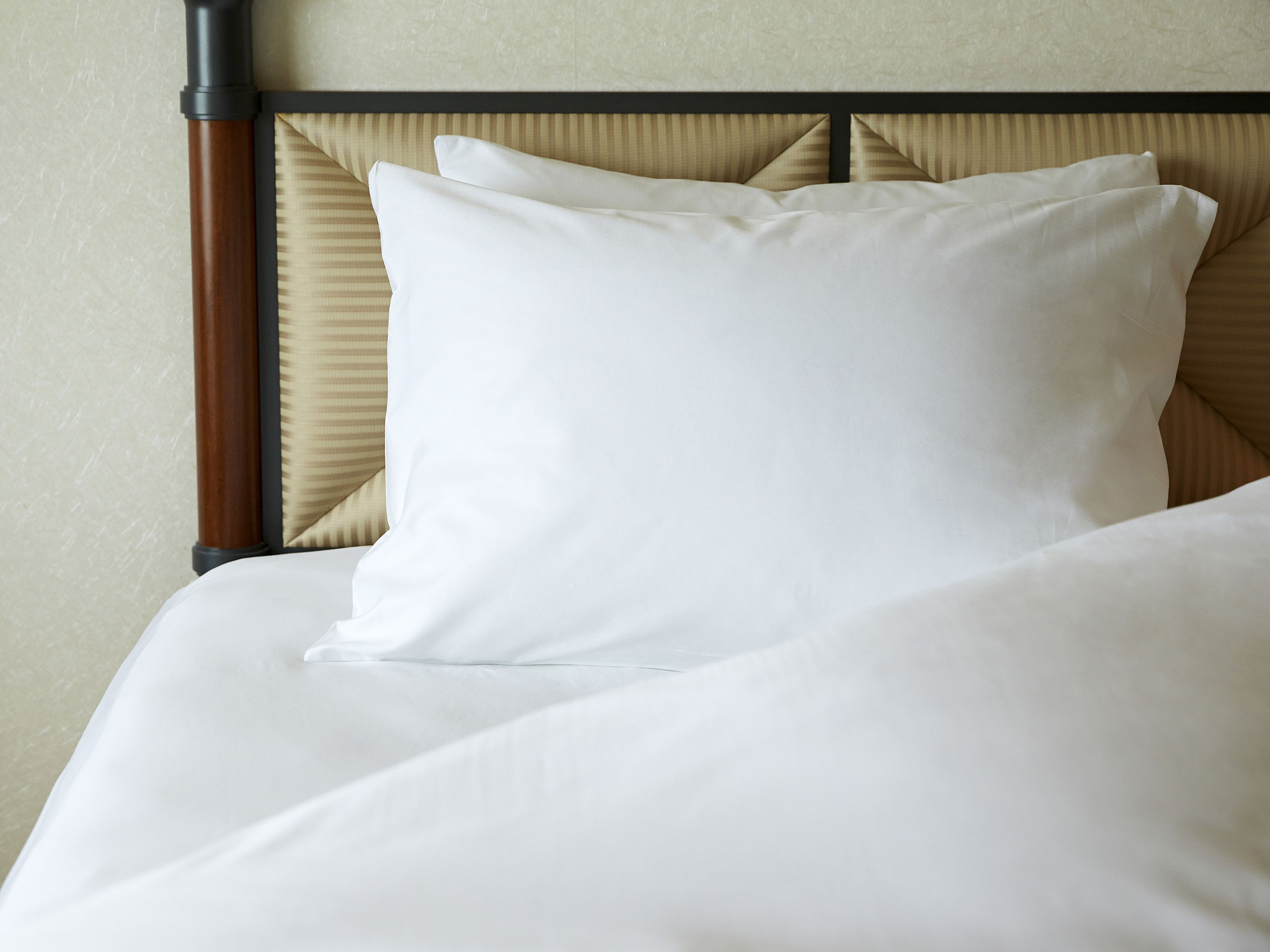 Una cama bien hecha con sábanas blancas y cabecera de madera.