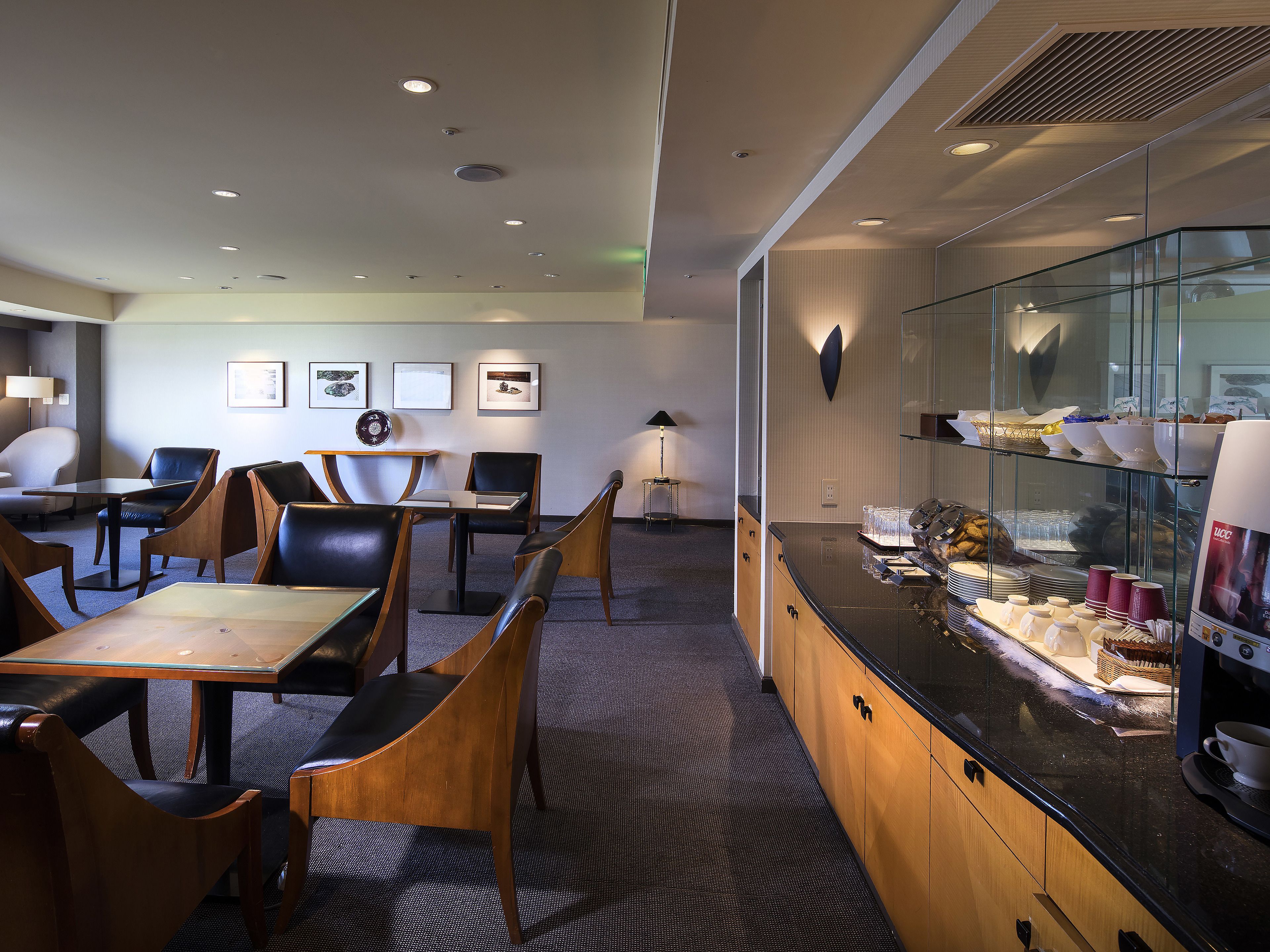 Un hall de hotel con una zona de estar, un mostrador de recepción y una vitrina de vidrio con productos alimenticios.