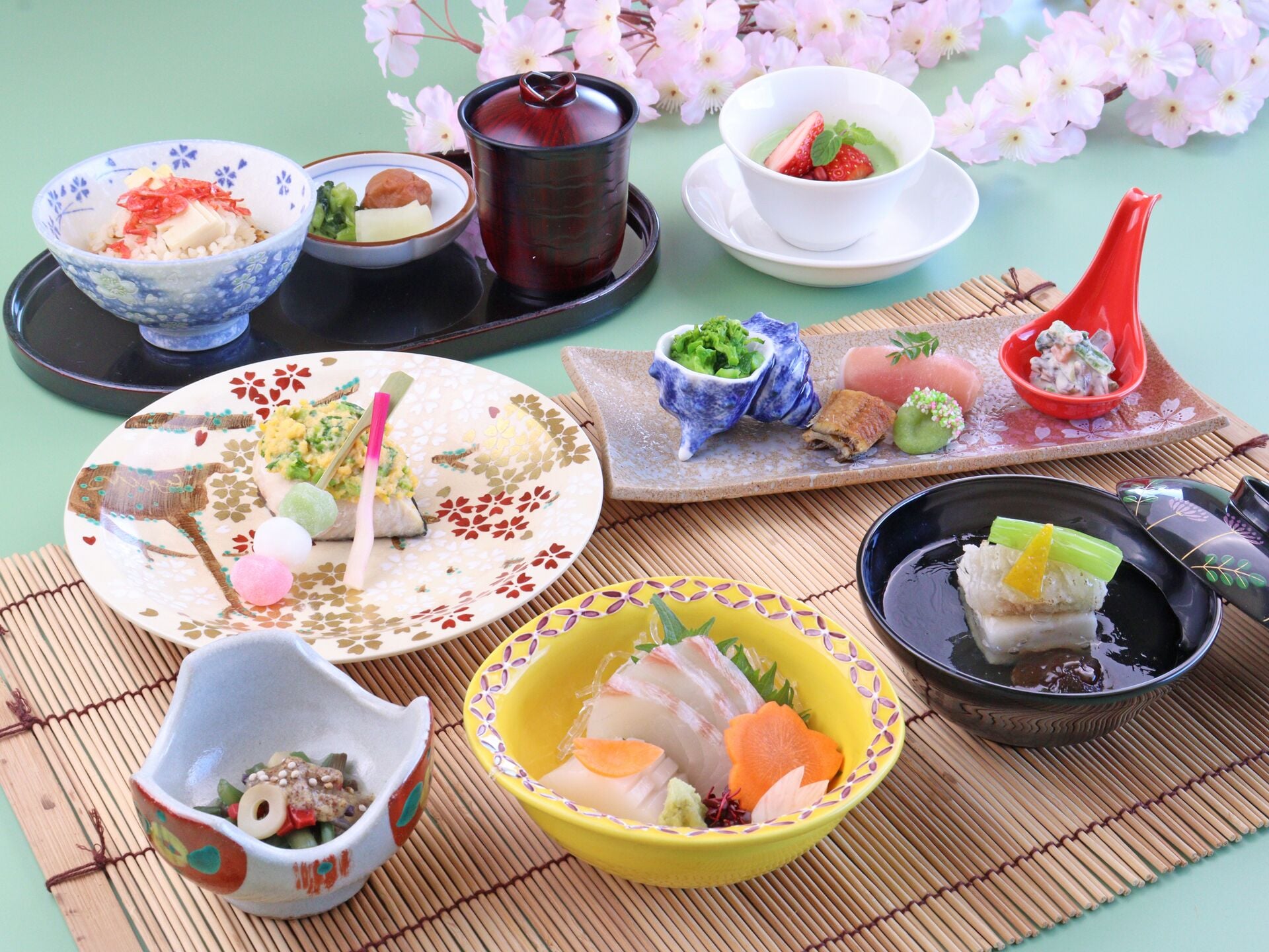 A variety of Japanese dishes arranged on a table with a bamboo mat underneath.
