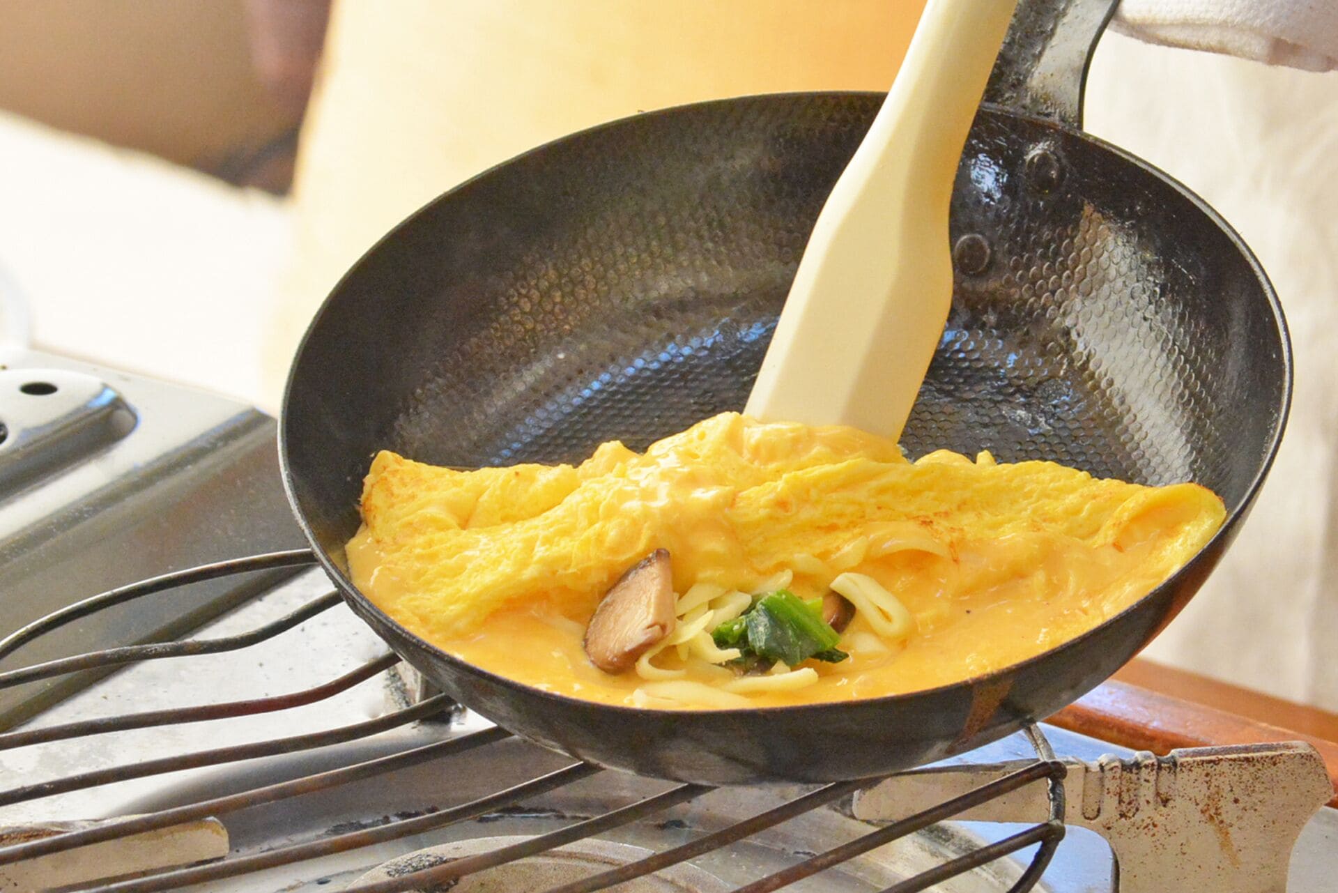 A frying pan with scrambled eggs and vegetables on a stove.