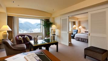 A hotel room with a desk, chair, and a bed. There is a window with a view of mountains.