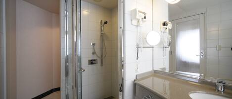 Un baño moderno con ducha de vidrio, un espejo grande y piso de baldosas de mármol.