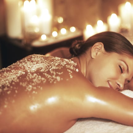 A person receiving a massage in a dimly lit room with candles.