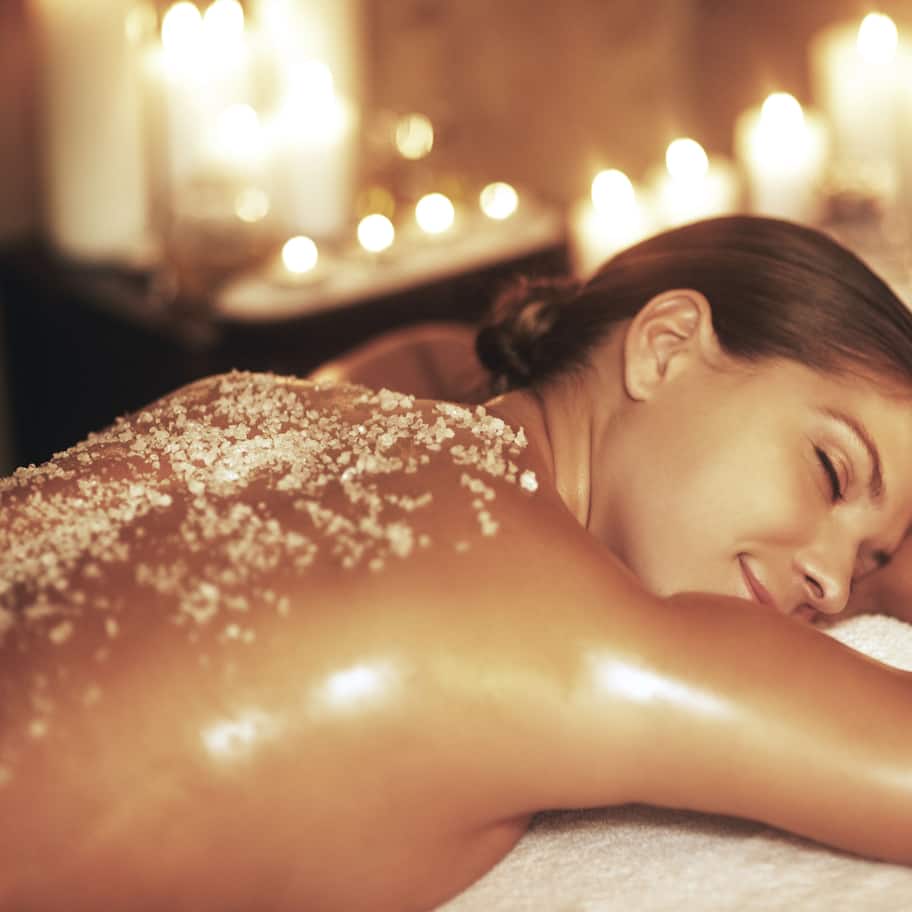 A person receiving a massage in a dimly lit room with candles.