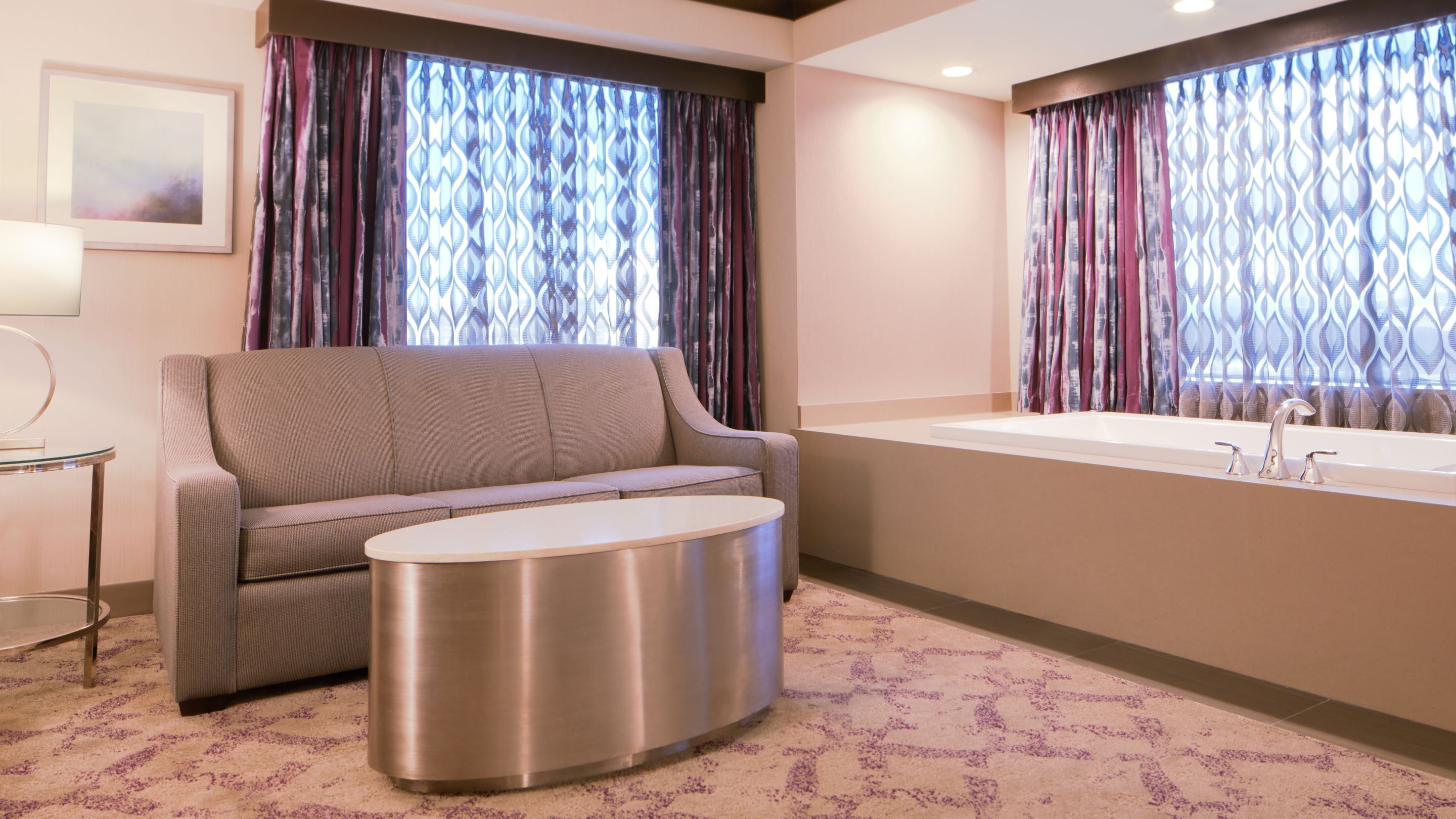 A modern bathroom with a sofa, a round table, and a bathtub.