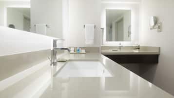 A modern bathroom with a large mirror, two sinks, and a towel rack.