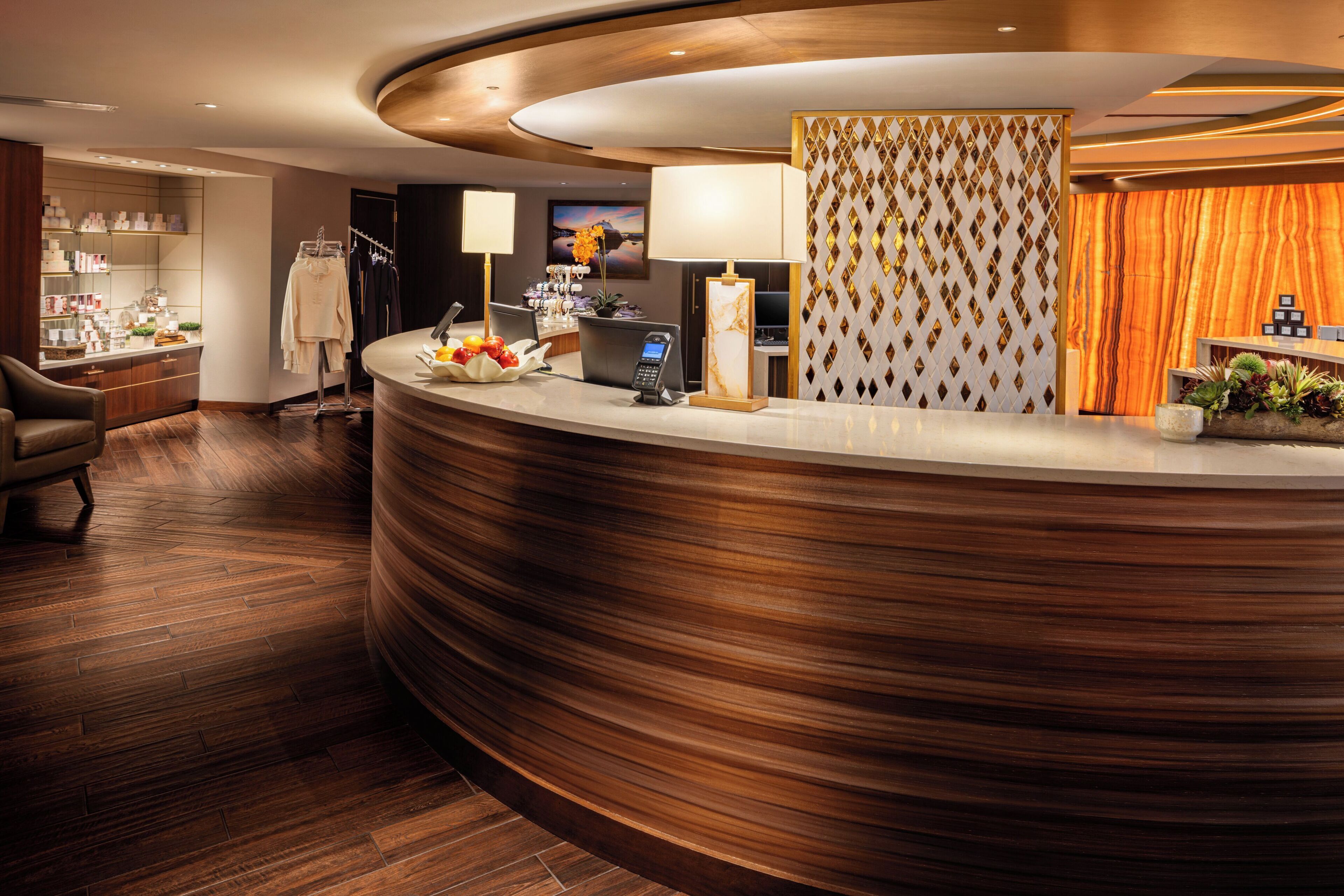A hotel reception area with a curved reception desk, a seating area with a chair, and a wall with a patterned design.