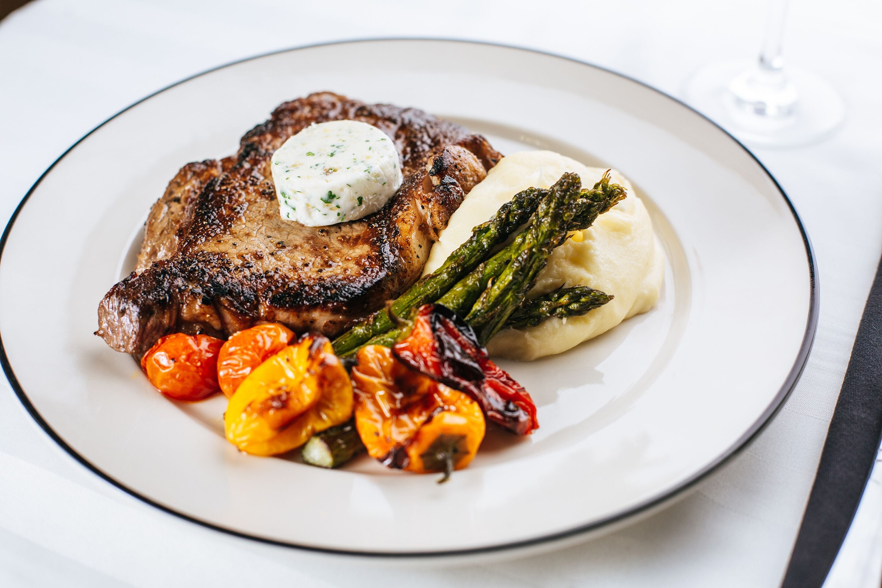 A plate of food with steak, asparagus, and roasted vegetables.
