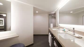 A modern bathroom with two sinks, a large mirror, and a towel rack.