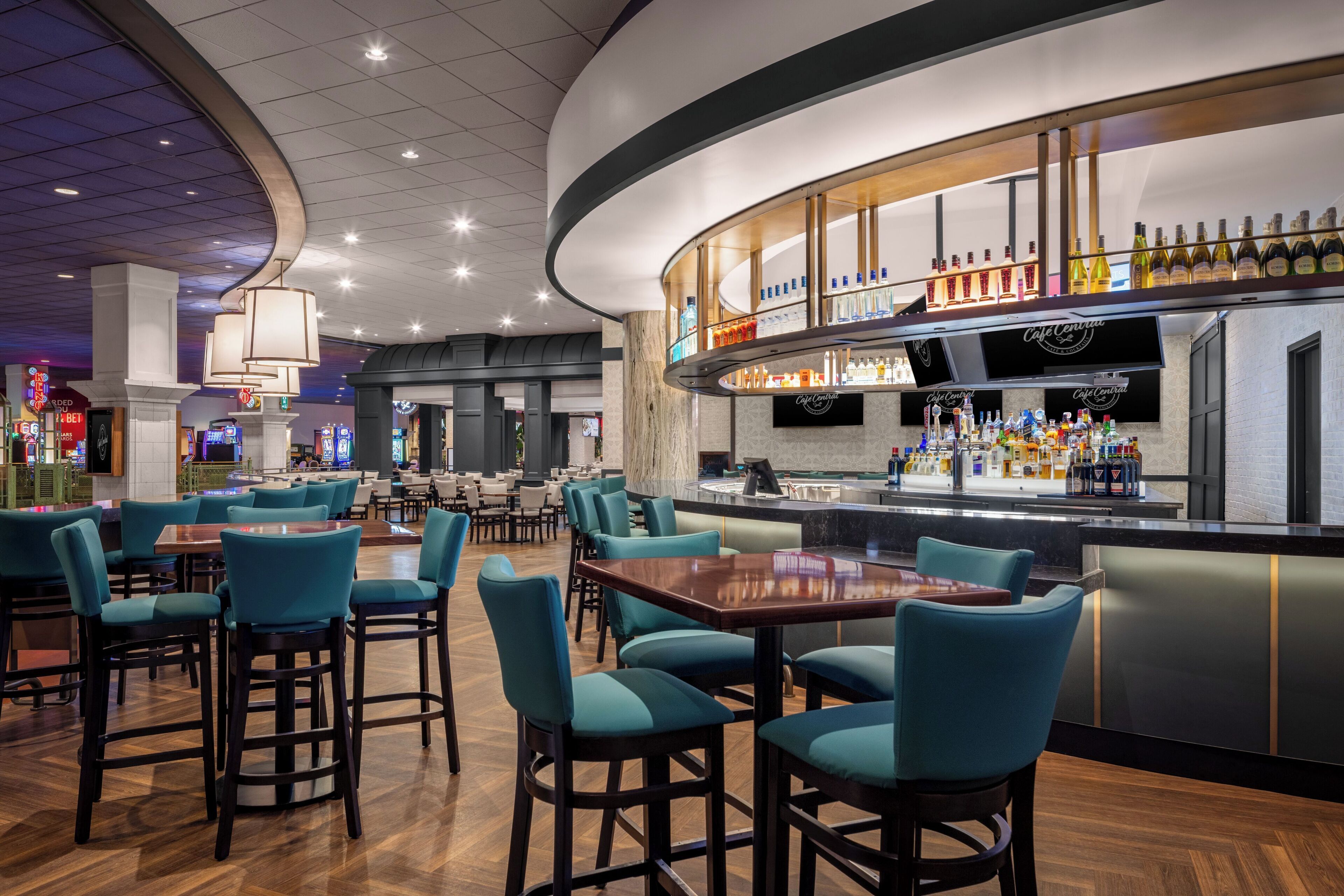 Uma área de bar moderna com balcão curvo, diversas opções de assento e variedade de garrafas de bebidas.