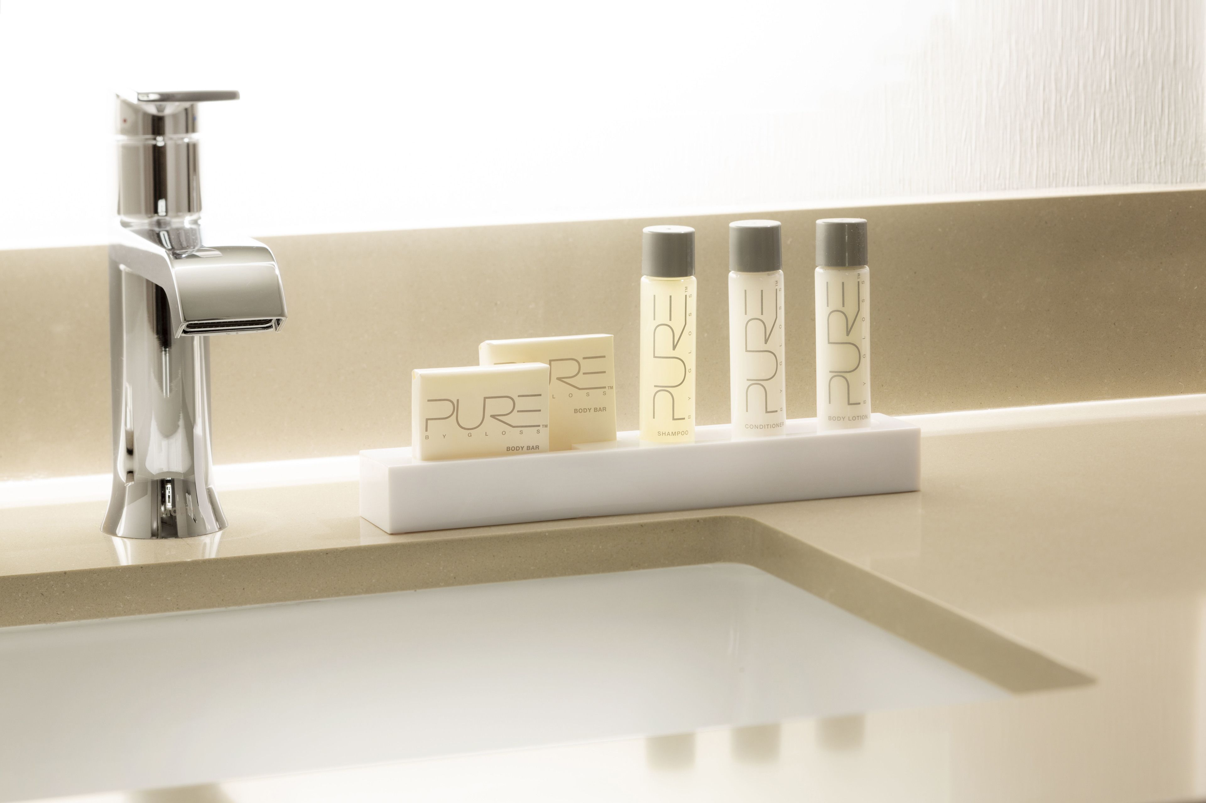 Un lavabo de bany amb un aixeta modern i una prestatgeria plena de productes de cura corporal.