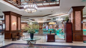 A grand lobby with chandeliers, a glass table, and a fountain.
