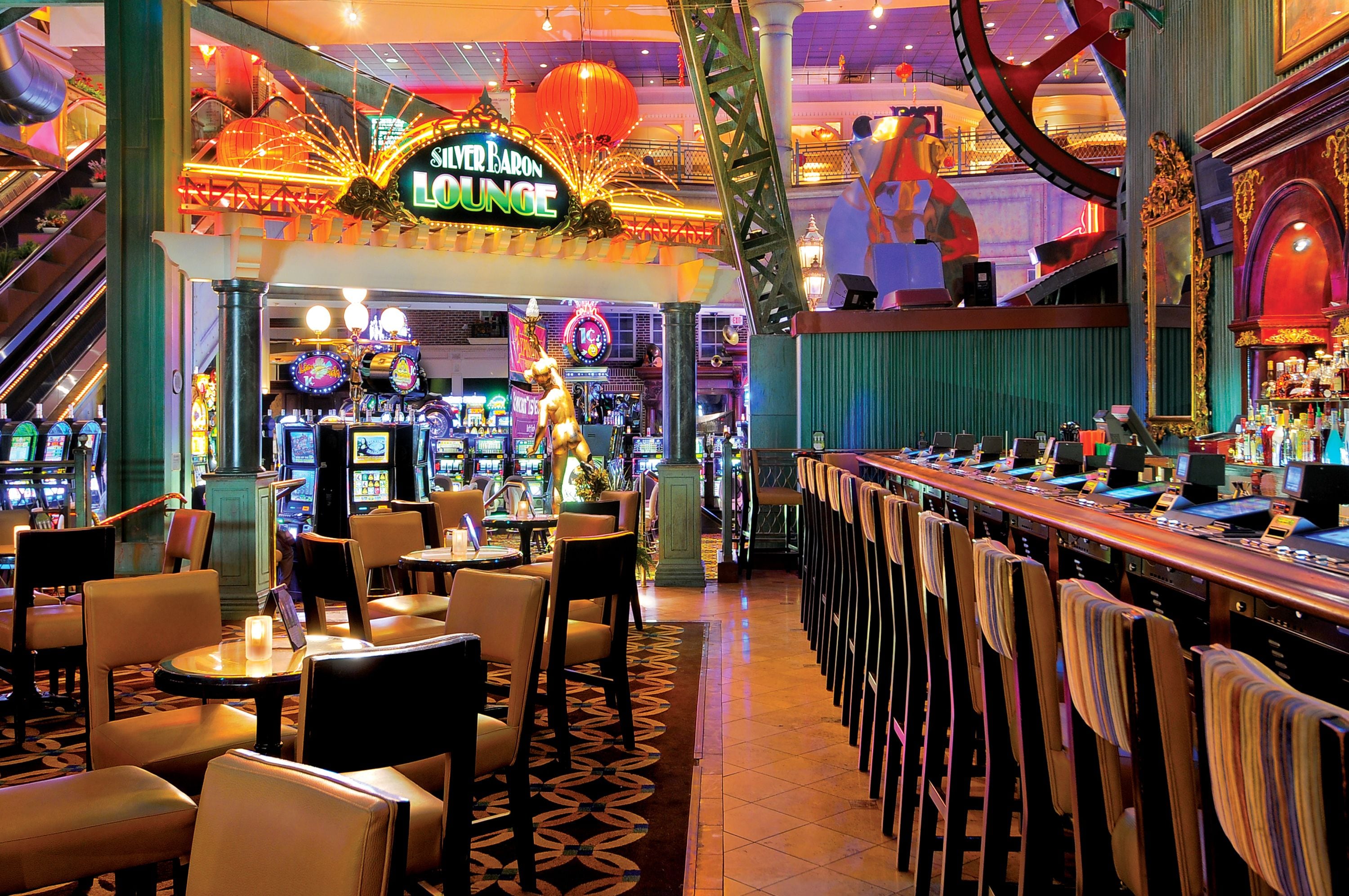 A bar area with a neon sign reading "Silver Baron Lounge," gaming machines, and a bar counter with chairs.