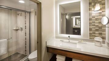 A modern bathroom with a glass-enclosed shower, a white sink, and a large mirror.