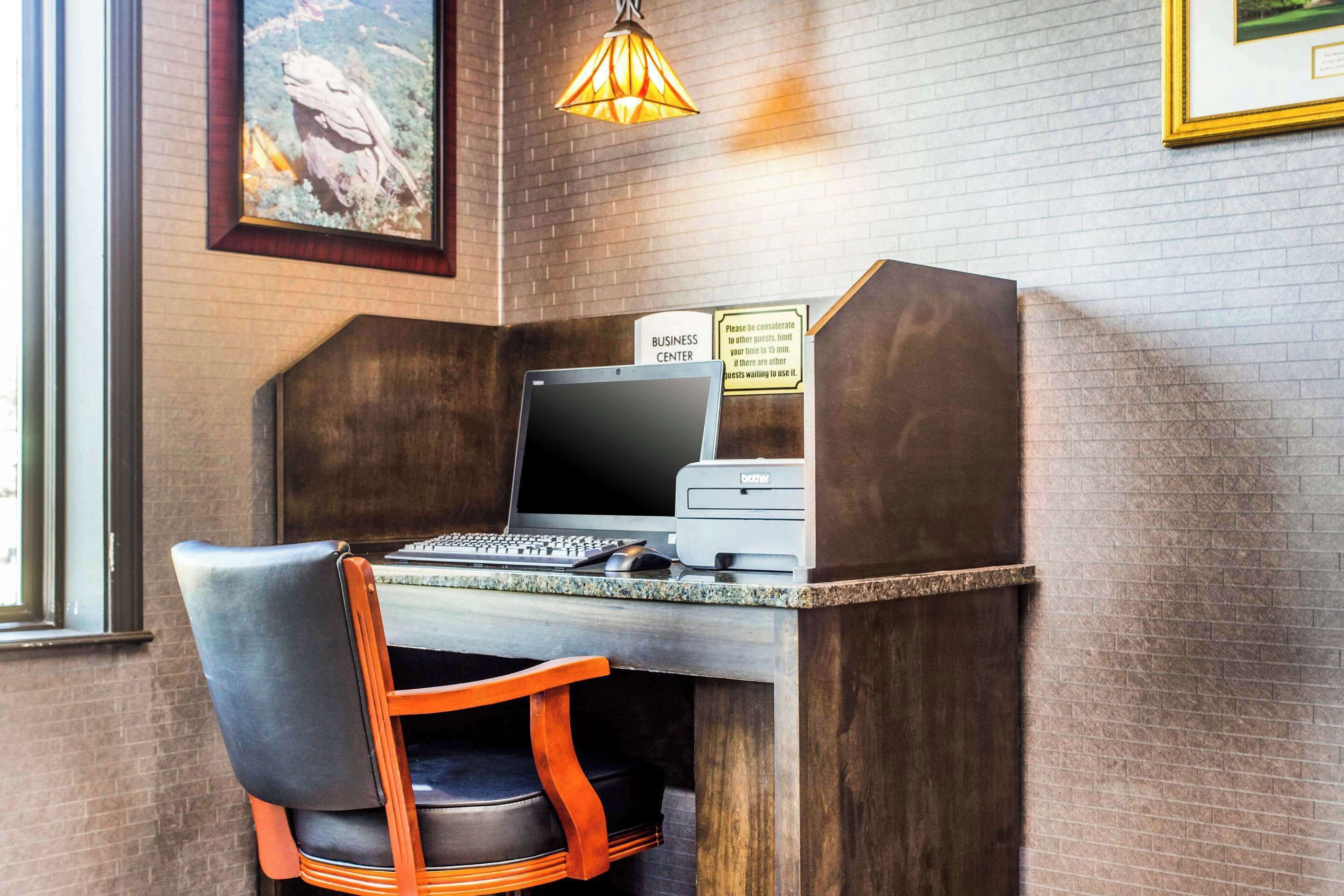 A business center with a computer, printer, and a chair.