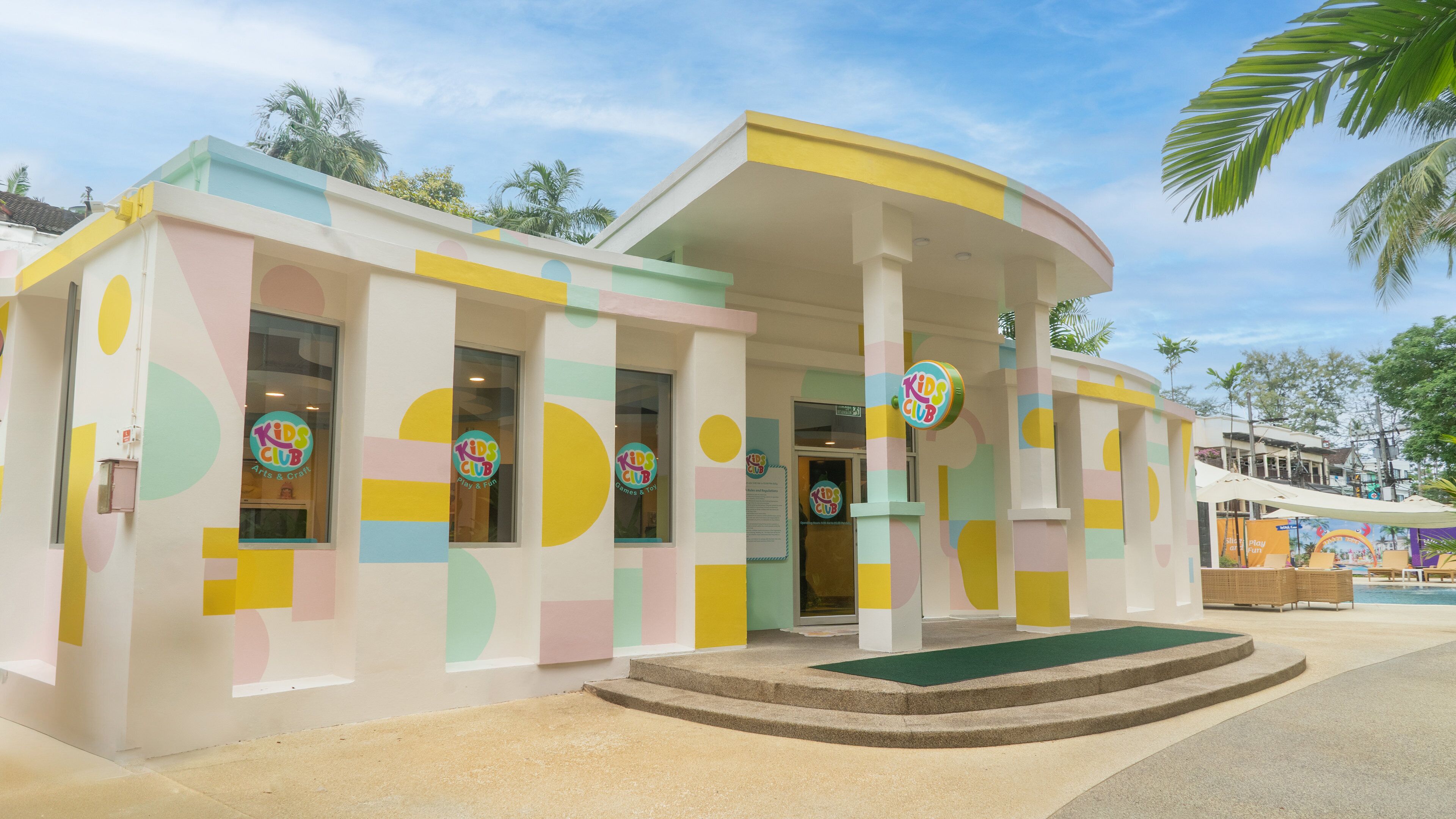 A colorful building with a Kids Club sign, featuring pastel walls and a curved roof.
