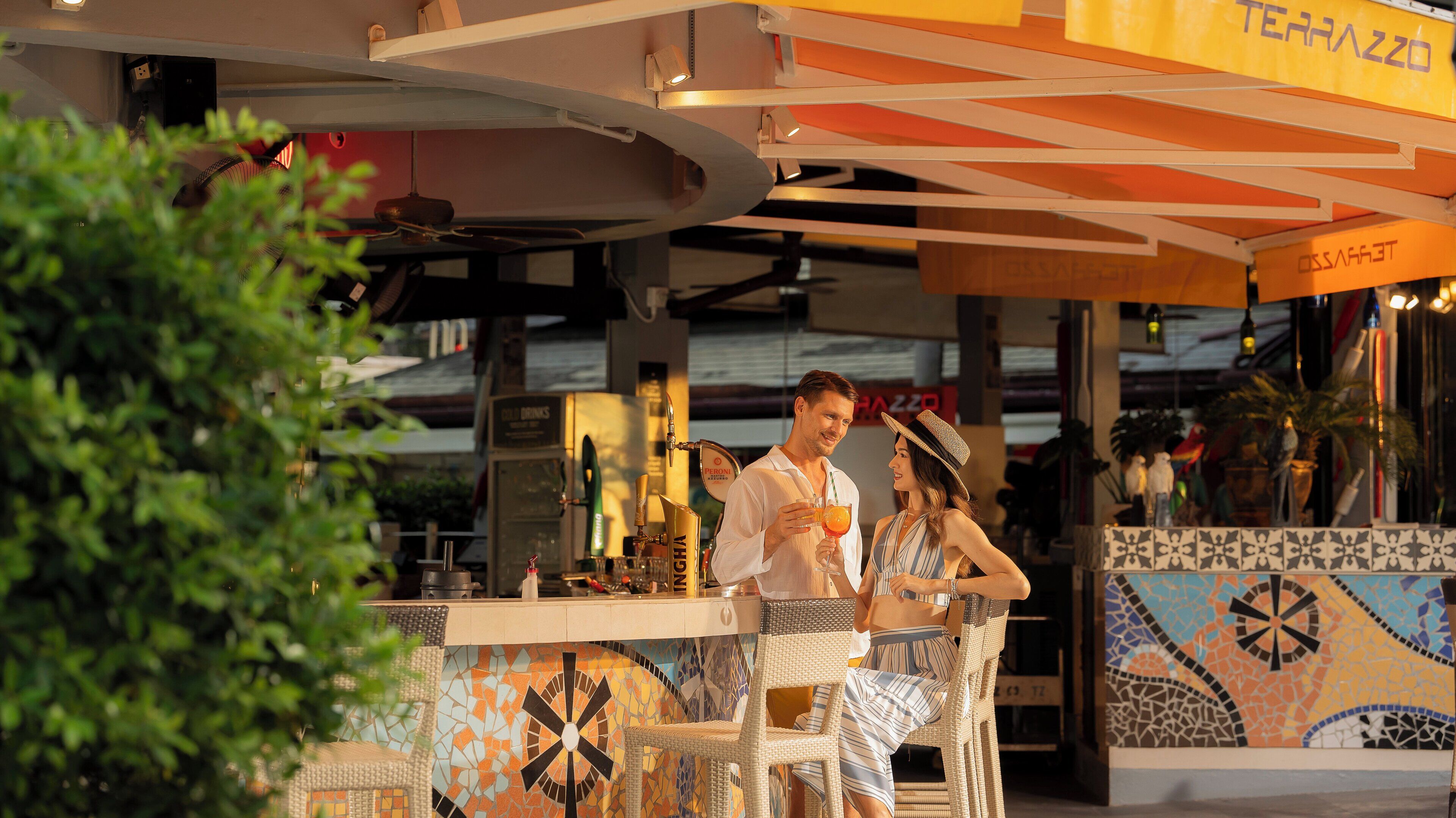 An outdoor bar area with a tiled floor, a counter with a cash register, and a sign that reads "TERRAZZO".