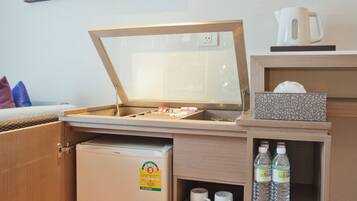 Una kitchenette compacta equipada con refrigerador, microondas, cafetera y un pequeño armario con botellas.