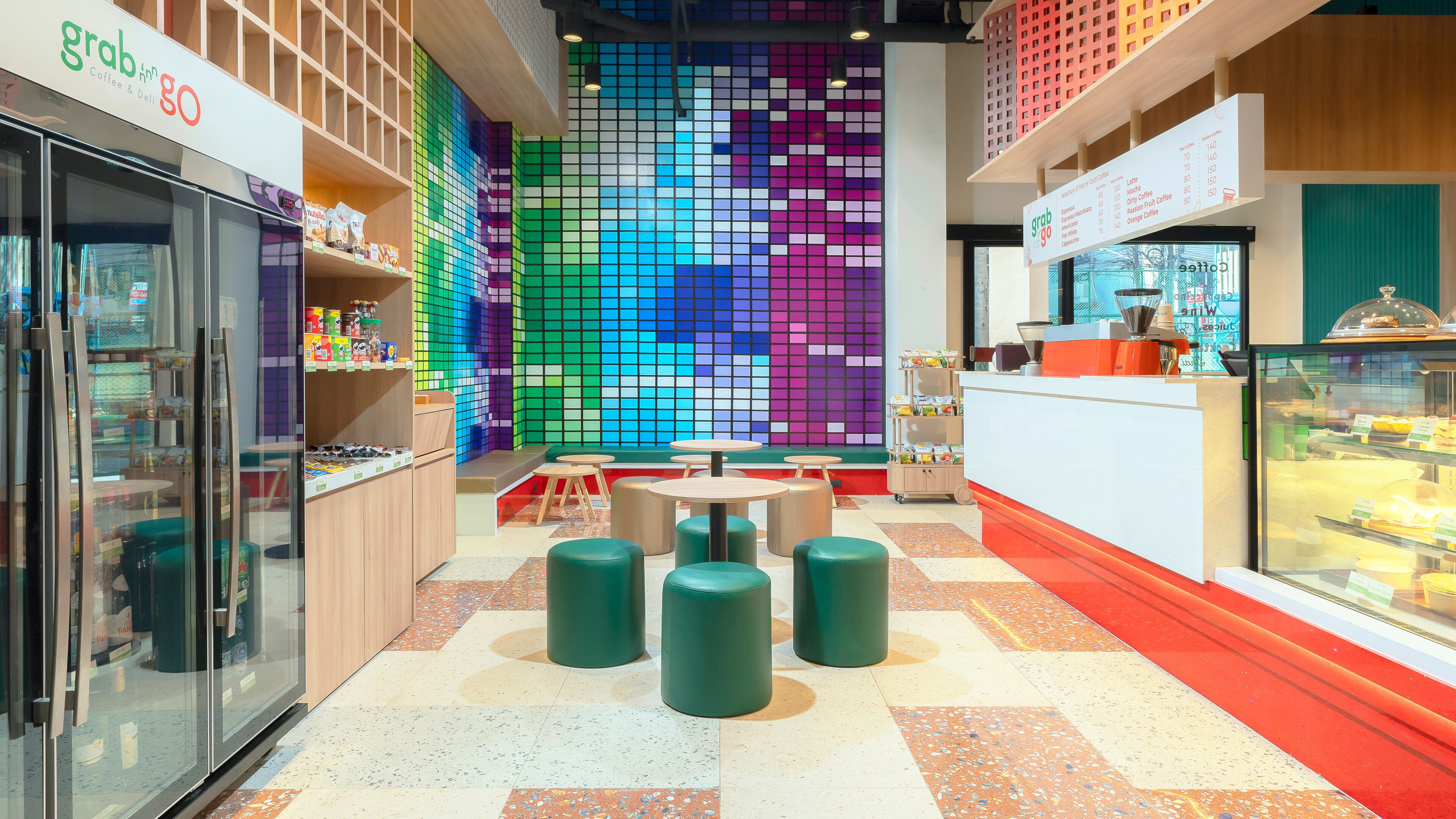 Un intérieur aux couleurs vives, comprenant un coin café, un espace salon et un mur orné d’un motif en mosaïque.