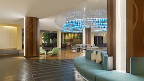 A spacious lobby with a modern chandelier, seating area, and a green wall with plants. - Holiday Inn Resort Phuket by IHG (Patong)