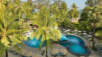 Relax by the resort's circular pool surrounded by palm trees and lounge chairs.