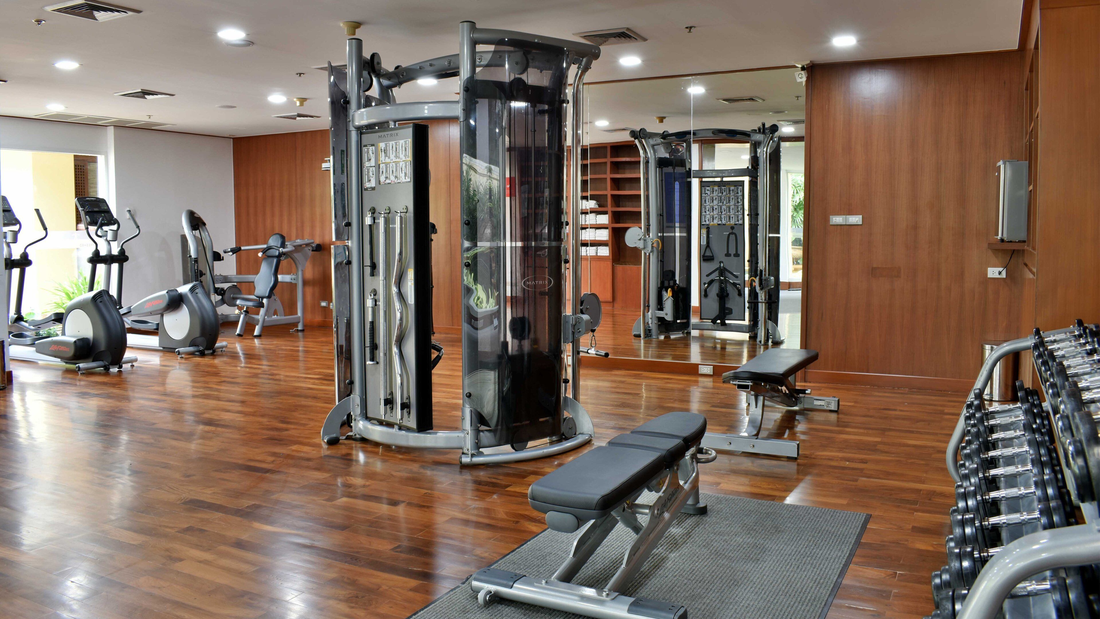 A gym with various exercise equipment, including a squat rack, treadmills, and free weights.