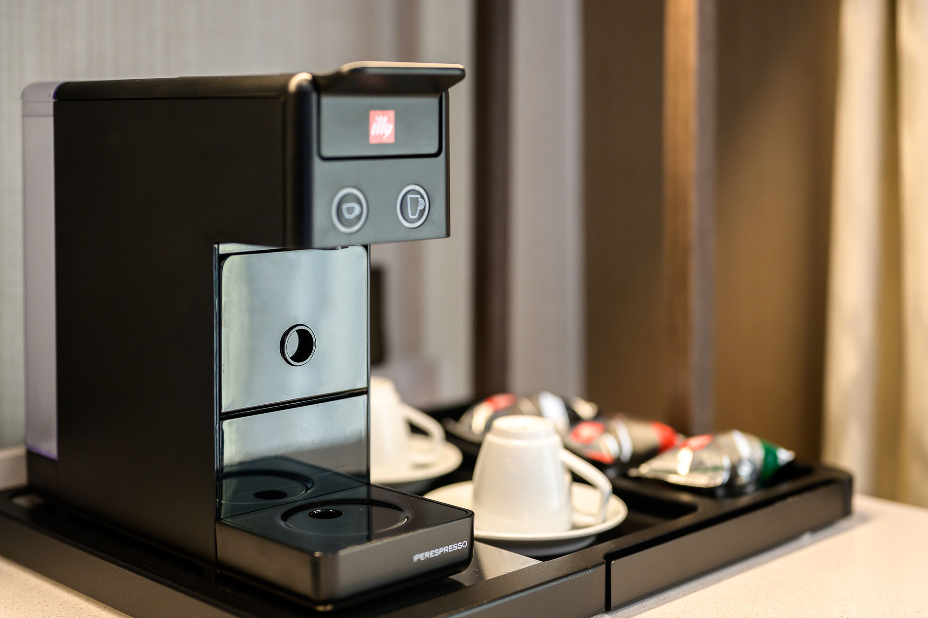 A compact espresso machine with a digital display and a coffee cup holder.