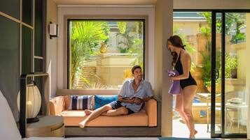 Habitación de hotel moderna con sofá, cama y un amplio ventanal con vistas al exterior.