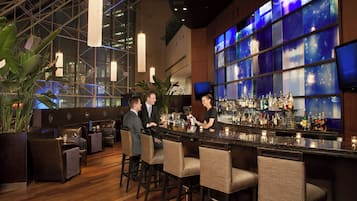A bar area with a high ceiling, large windows, and a variety of seating options.