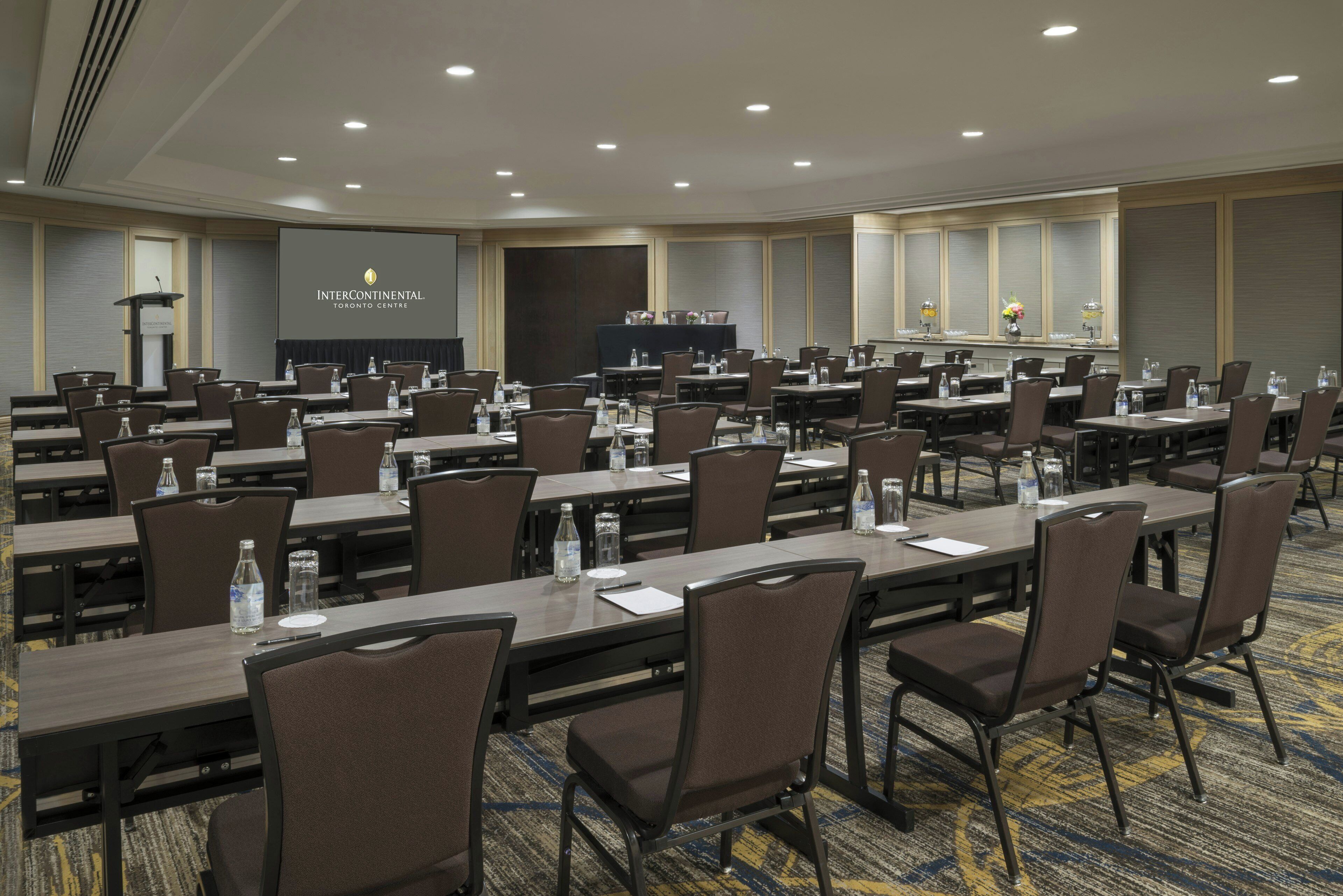 A conference room with multiple tables and chairs, equipped with water bottles and nameplates, at InterContinental Toronto Centre.