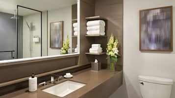 Un baño moderno con un espejo grande, un lavamanos, un inodoro y repisas con toallas.