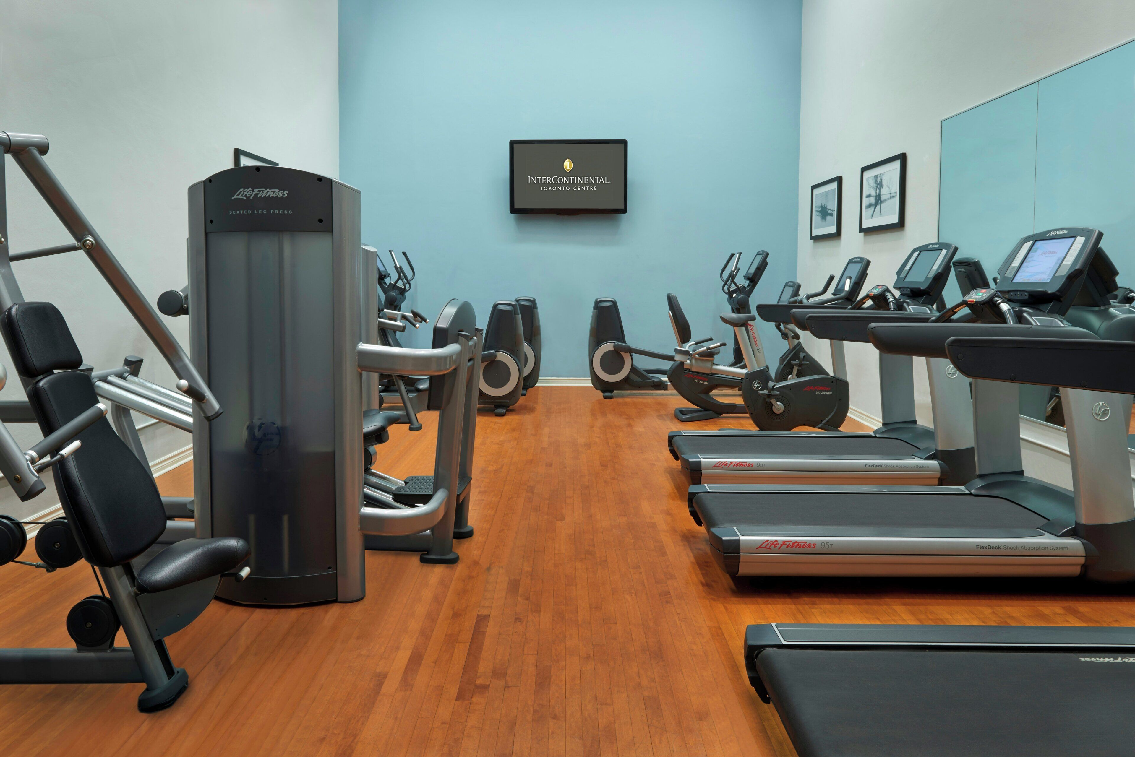 A gym with various exercise equipment including treadmills, stationary bikes, and weight machines.