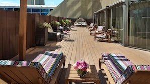 Una terraza con muebles de madera y vistas a una torre alta.