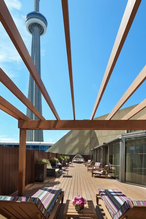 Una terraza con muebles de madera y vistas a una torre alta.