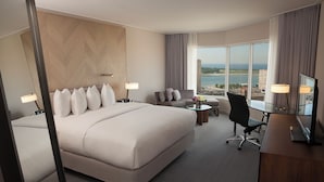 Habitación de hotel con una cama grande, un escritorio, una silla y vistas a la ciudad.