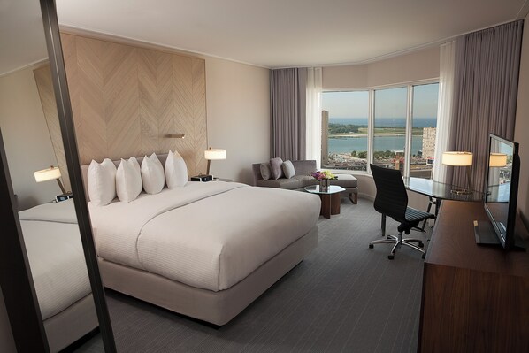 Habitación de hotel con una cama grande, un escritorio, una silla y vistas a la ciudad.