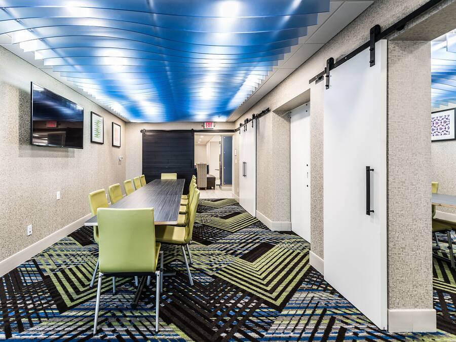 A conference room with a long table and chairs, a patterned carpet, and a blue ceiling.
