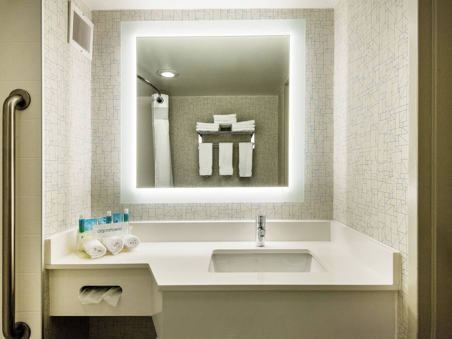 A bathroom with a white sink, a mirror, and a towel rack.