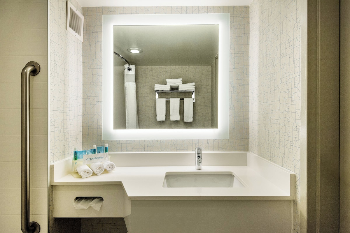 Une salle de bain moderne avec un lavabo blanc, un miroir et un porte-serviettes.
