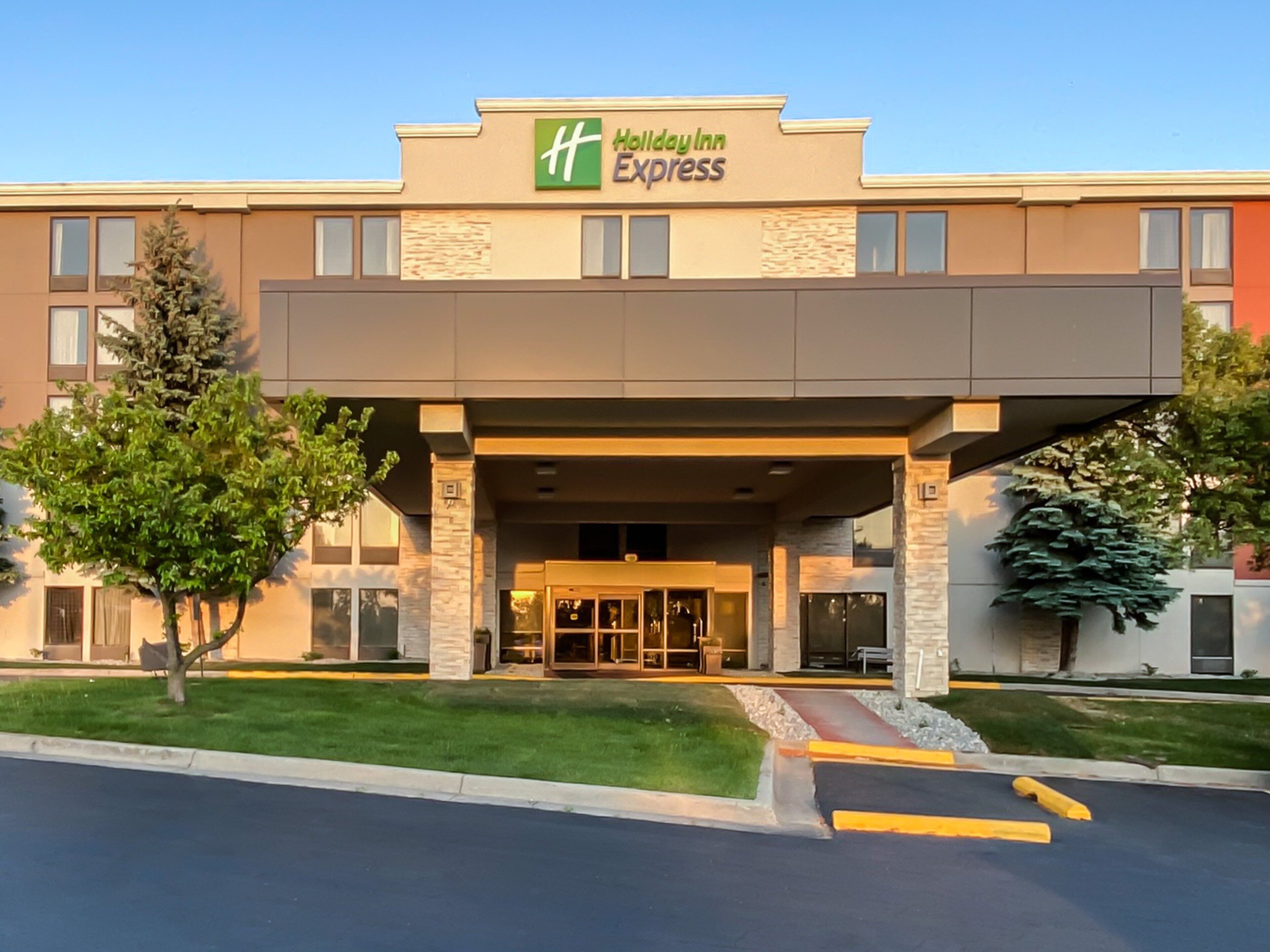 A Holiday Inn Express building with a modern entrance, a covered walkway, and a well-maintained lawn.