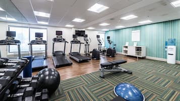 A fitness center with treadmills, elliptical machines, a rowing machine, free weights, and exercise balls.
