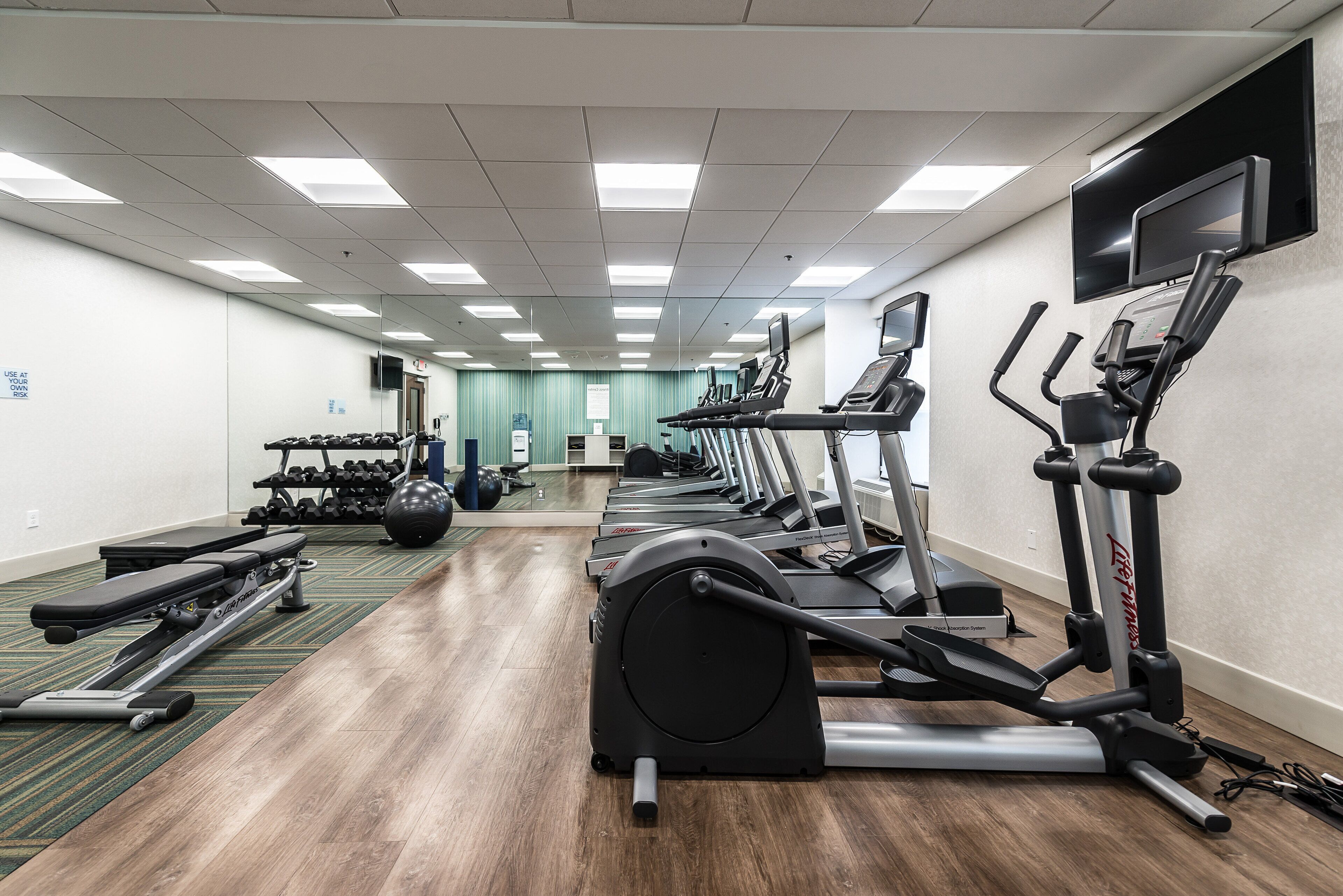 A gym with treadmills, elliptical machines, and weight equipment.